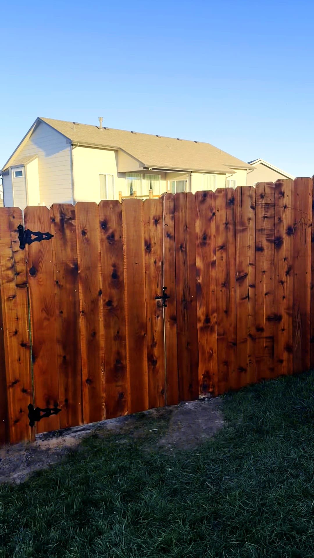 Red stained cedar privacy gate on black hinges, built by Ovora Outdoor in Maize, Kansas