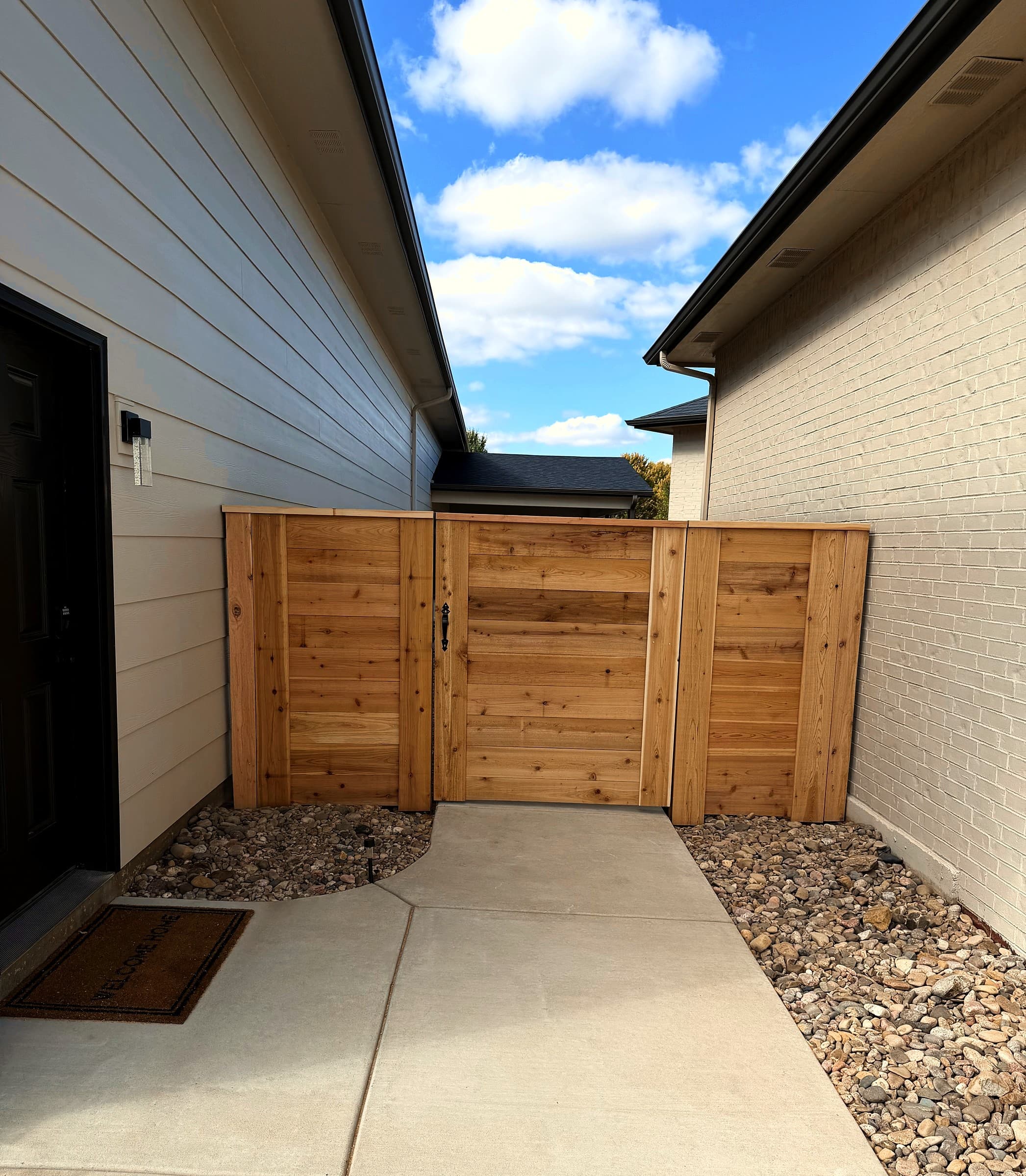 Horizontal cedar walk gate closing off a side yard, built by Ovora Outdoor in Andale, Kansas