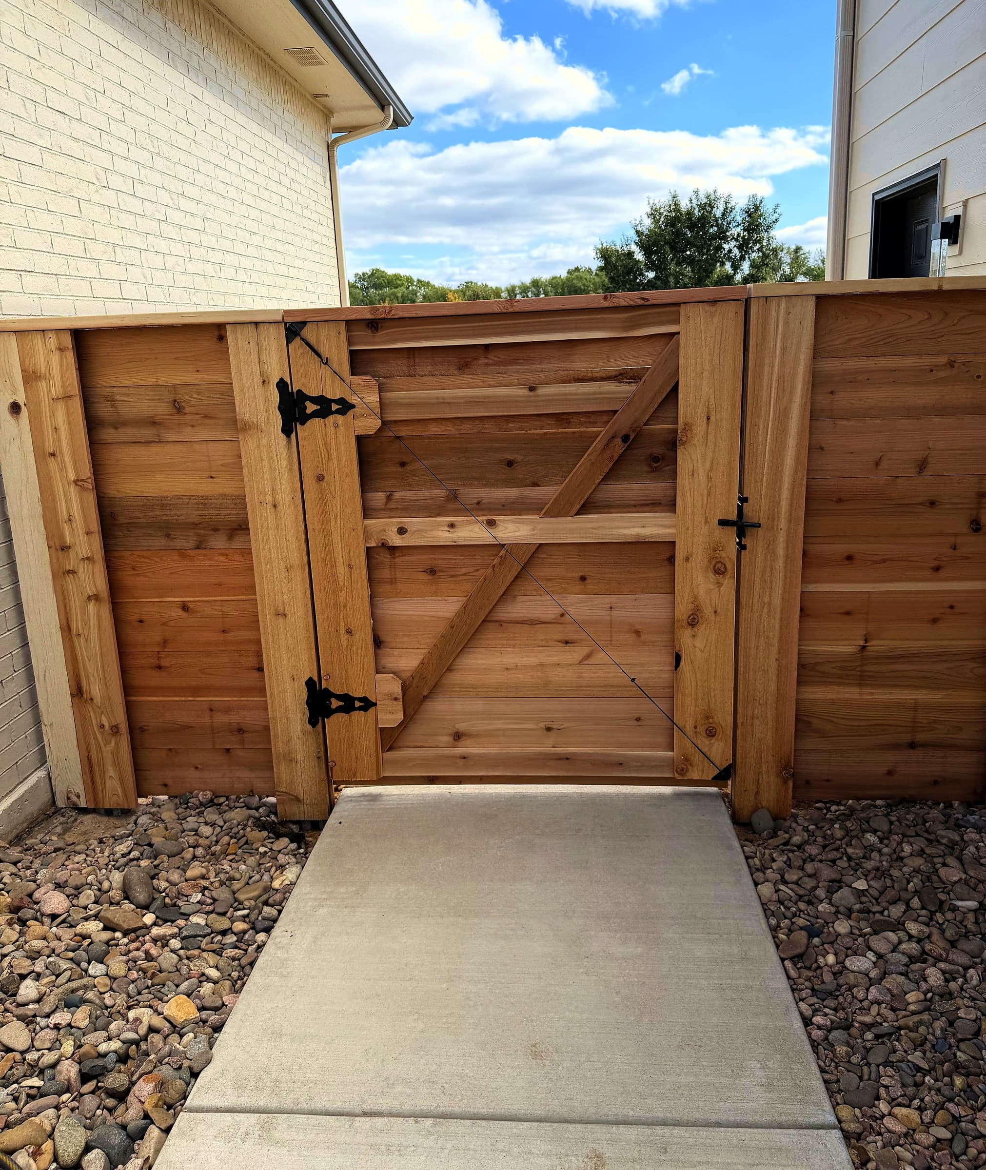 Inside of a horizontal cedar gate with a diagonal brace and black hinges, in Andale, Kansas