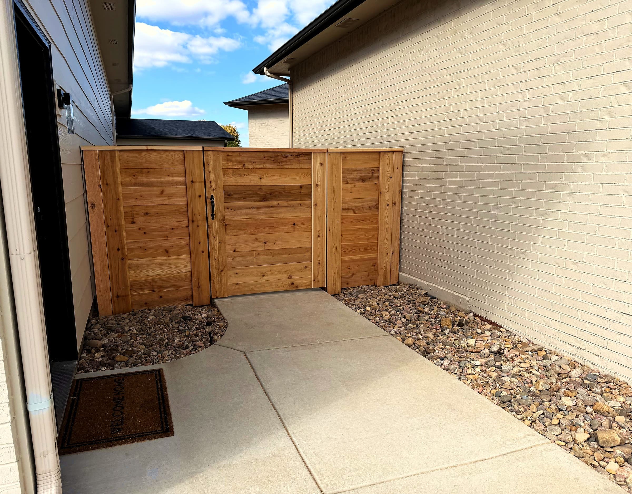 Horizontal cedar fence and walk gate beside a brick home in Andale, Kansas